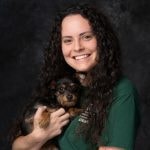 Megan Connell, Finance Coordinator, holding a dachshund puppy.