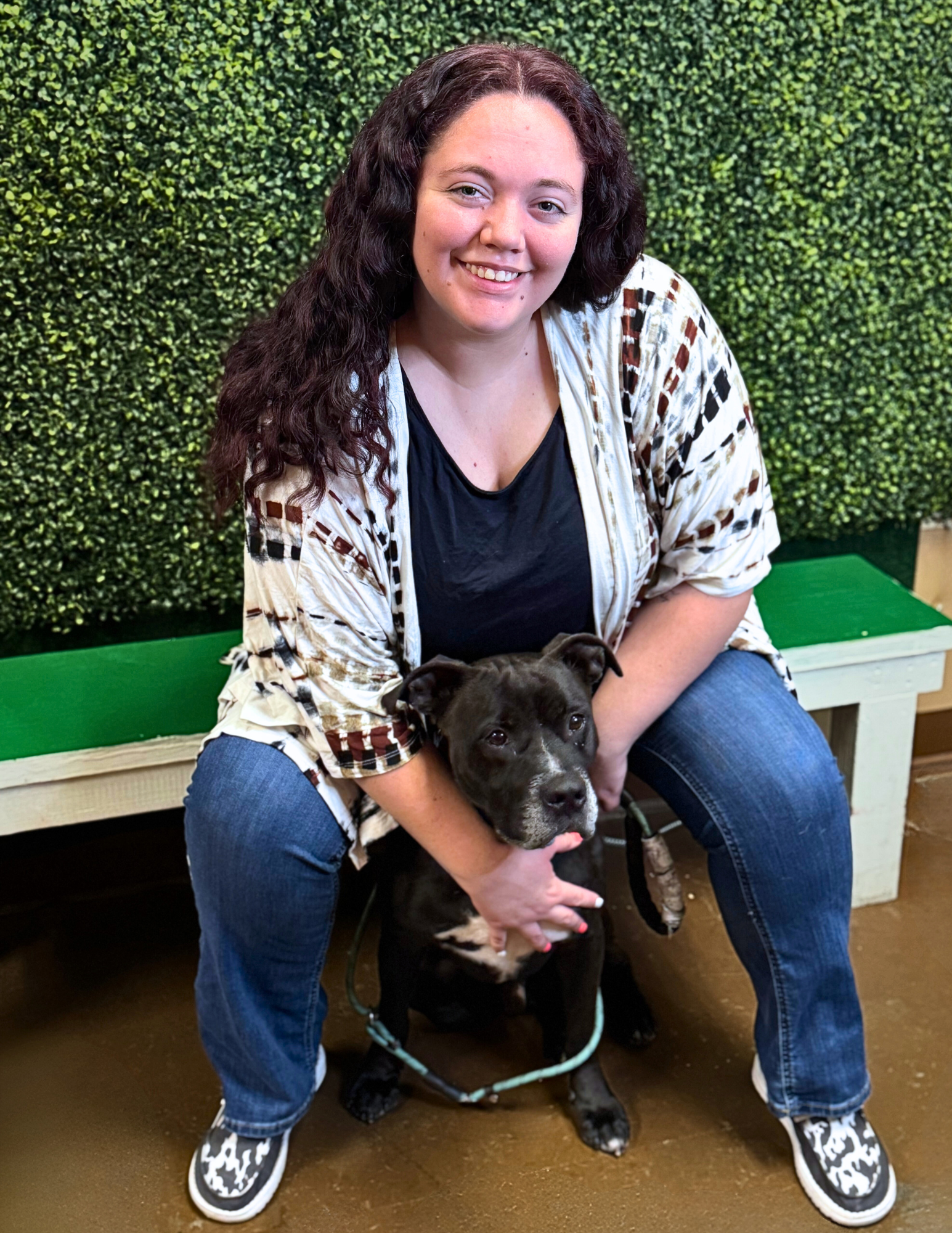 Taylor Kline, Corporate Adoption Coordinator, posing with a black dog.